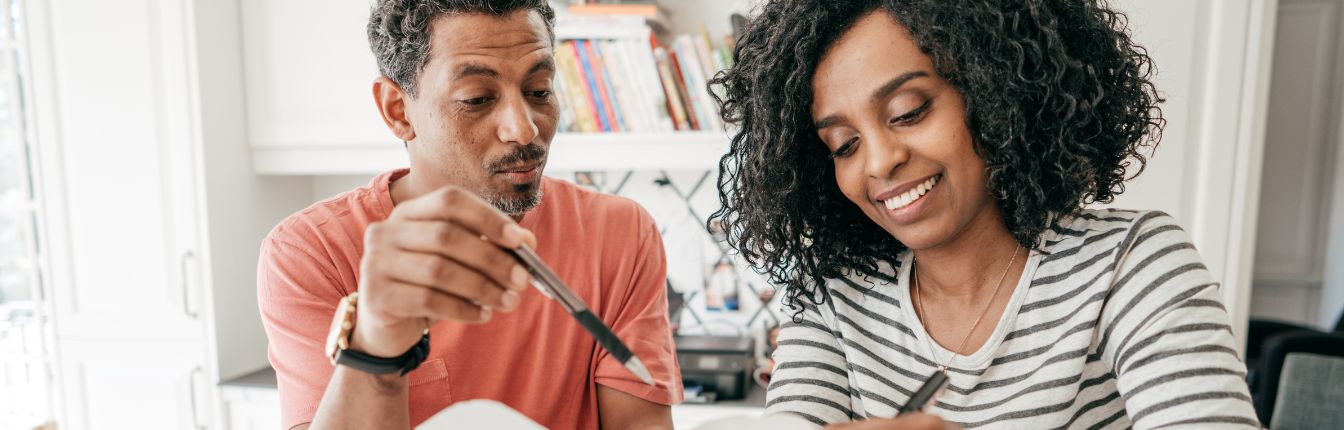 A couple looking over financial paperwork while sitting at a table together.