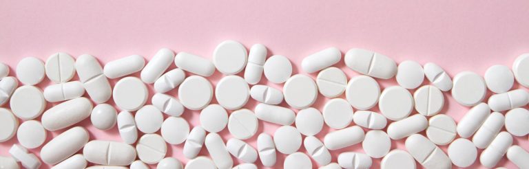 White pills on a light pink background.