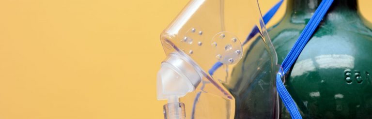 An oxygen tank and oxygen mask, against a yellow background.